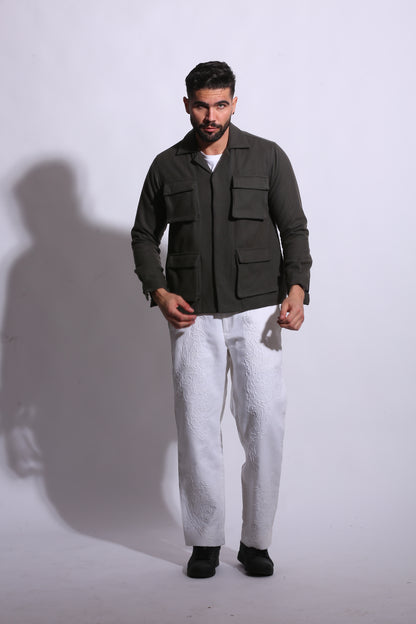 Man in a dark coat standing on a white floor with a plain background