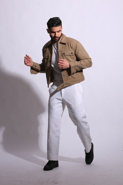 Man wearing a beige trench coat and white pants on a white background