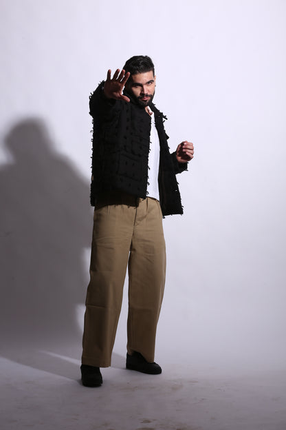 Person wearing a black and brown outfit with a textured sleeve against a white background