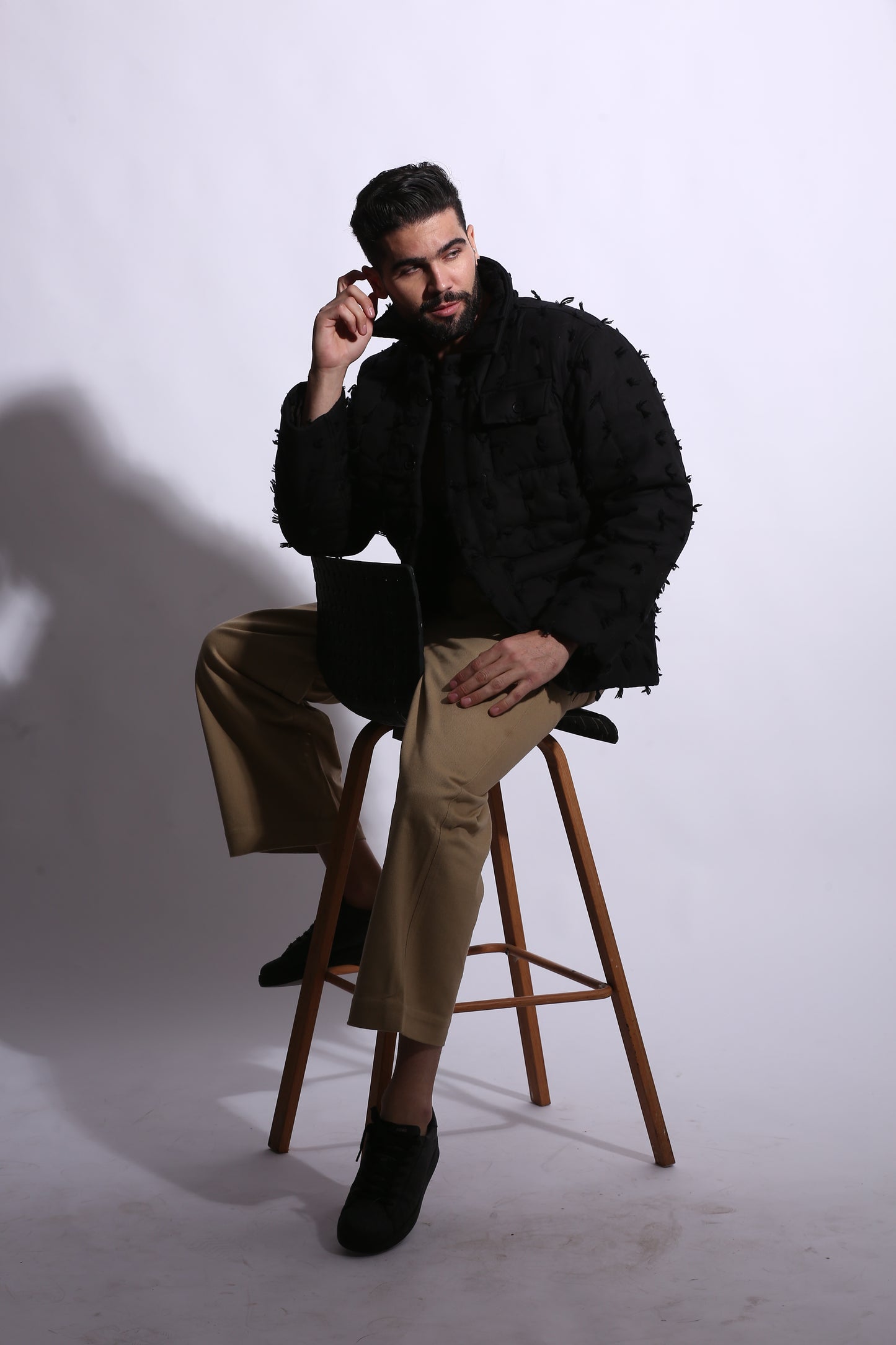 Person sitting on a stool with a white background