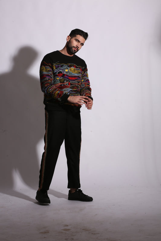 Person wearing a colorful sweater and black pants on a white background