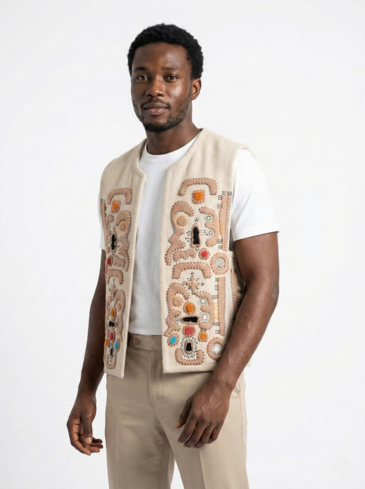 Man wearing a beige embroidered vest over a white shirt on a white background